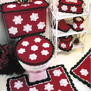 May include: A crocheted bathroom set with a snowflake design. The set includes a toilet tank cover, toilet seat cover, tissue box cover, soap dish, and two bath mats. The set is red and white with green trim.