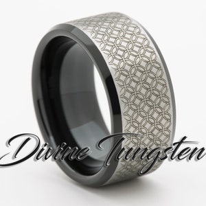 May include: A black tungsten ring with a silver band featuring a geometric pattern. The ring has a beveled edge and a polished finish.