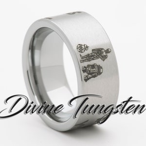 May include: A silver tungsten ring with an engraved design of Star Wars characters R2-D2, C-3PO, and a Death Star. The ring is brushed and has a beveled edge.