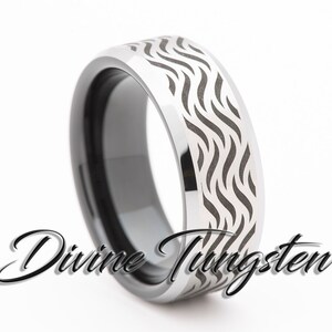 May include: A silver tungsten ring with a black inlay and a wave pattern engraved on the top. The ring is a brushed finish and has a beveled edge.
