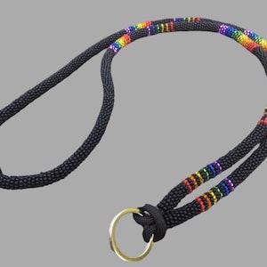 Könnte beinhalten: Ein schwarzes Lanyard mit einem Regenbogenstreifen-Design und einem goldenen Schlüsselring.