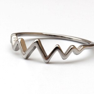 Può includere: Una tazza di ceramica bianca con manico nero e la scritta "But First, Coffee" in grassetto nero. La tazza è posta su uno sfondo sfocato, che suggerisce un'atmosfera accogliente.