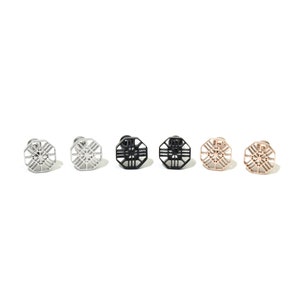 Op de afbeelding: Zes paar oorbellen met een geometrisch ontwerp. De oorbellen zijn zilver, zwart en roségoud.