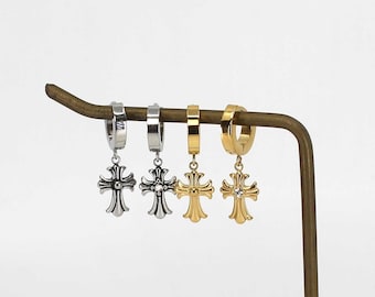 May include: Four pairs of silver and gold hoop earrings with a dangling cross charm. Each cross charm has a single clear rhinestone in the center.