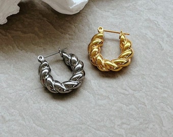 May include: A pair of hoop earrings, one gold and one silver, with a twisted rope design.