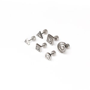 May include: Set of six silver stud earrings with geometric designs. The earrings feature a triangle, square, and spiral pattern.