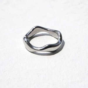 May include: A silver ring with a wavy, organic shape.