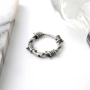 Op de afbeelding: Zilveren ring met een prikkeldraad ontwerp.