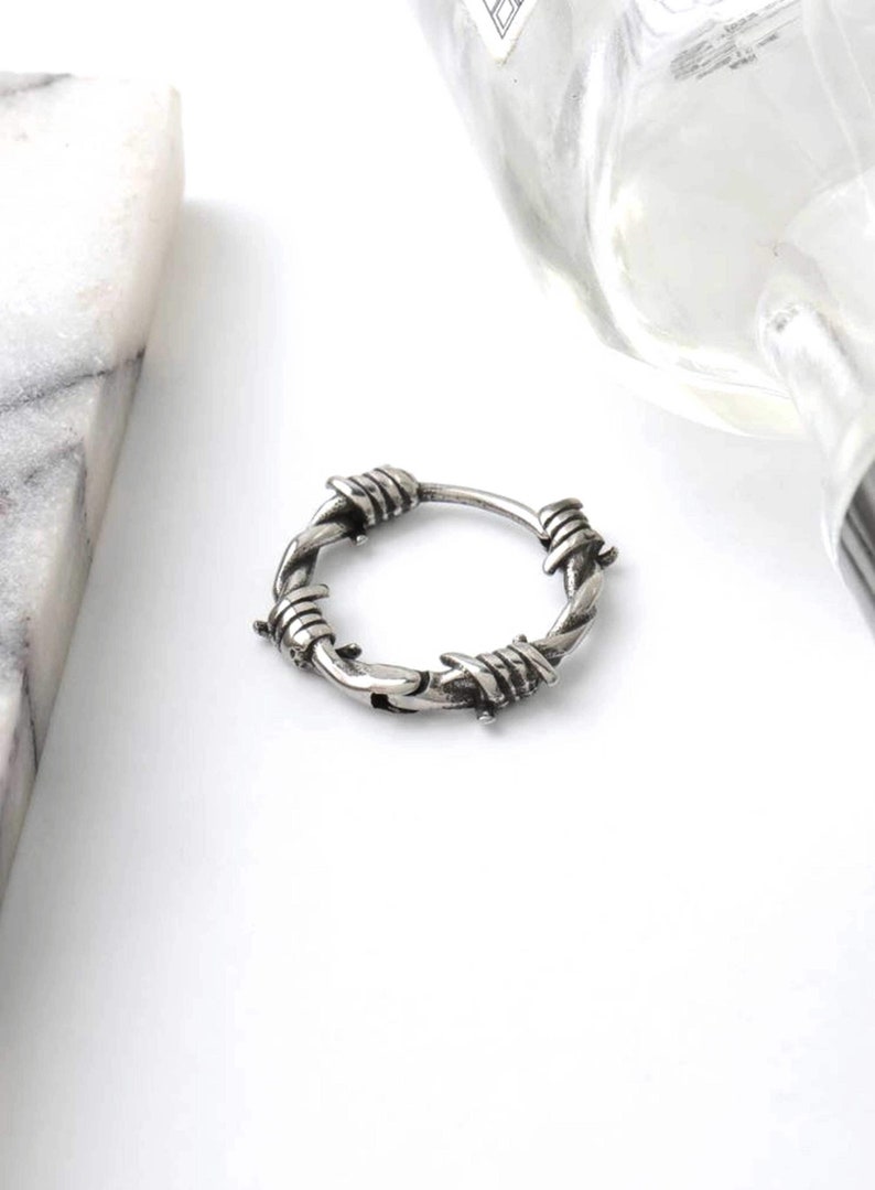 Op de afbeelding: Zilveren ring met een prikkeldraad ontwerp.