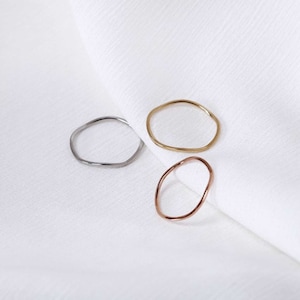 Könnte beinhalten: Drei schlichte, minimalistische Ringe in Gold, Silber und Roségold. Die Ringe sind alle leicht unregelmäßig geformt, was ihnen einen einzigartigen und modernen Look verleiht.