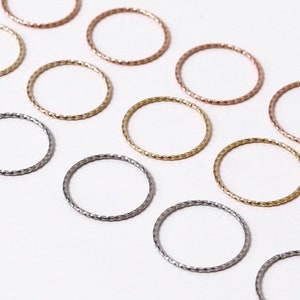 May include: A set of nine delicate, twisted metal rings in silver, gold, and rose gold. The rings are arranged in a row on a white background.