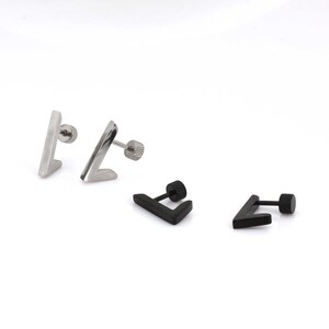 May include: A selection of V-shaped stud earrings in silver and black. The silver earrings are polished, and the black ones have a matte finish. The earrings are presented against a white backdrop.