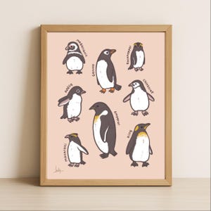 May include: A framed print featuring cartoon illustrations of various penguin species, including Emperor, King, and Adelie penguins. Each penguin is depicted in black, white, and yellow, with their names written in a handwritten font. The background is a soft peach color.