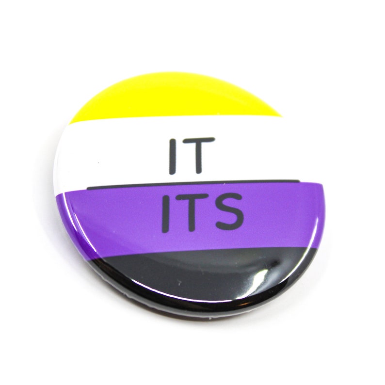 May include: A round button with the words "IT ITS" in black text on a white background. The button has a yellow, white, purple, and black striped design.