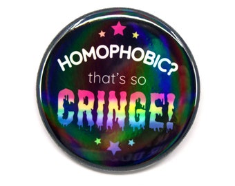 May include: A round button with a holographic, iridescent finish. The button features the text "HOMOPHOBIC? that's so CRINGE!" in white and rainbow colors, with pink stars.
