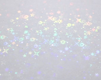 Puede incluir: Un fondo blanco con un degradado de estrellas iridiscentes esparcidas por la superficie.