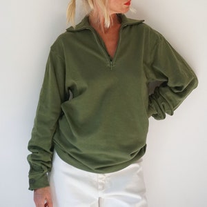May include: A green, long-sleeved, collared sweatshirt with a zip.