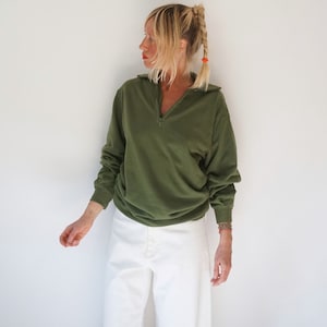May include: A green, long-sleeved, collared sweatshirt with a zip. The sweatshirt has a relaxed fit and is made of a soft, comfortable fabric.