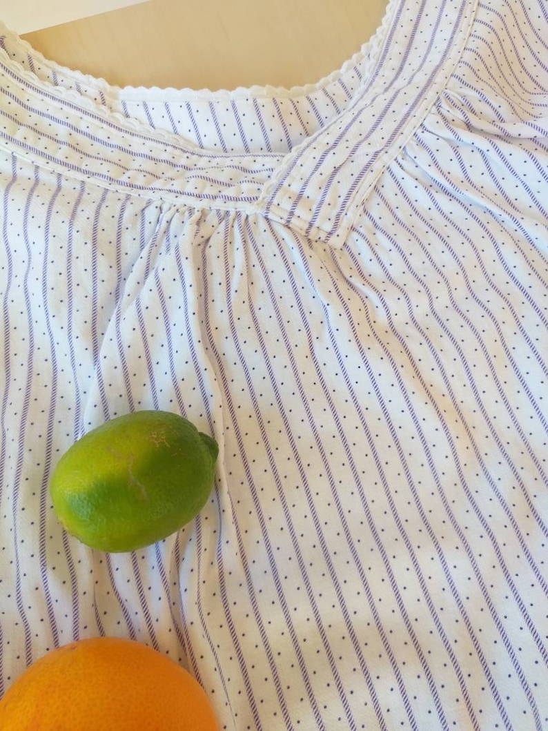May include: White cotton fabric with thin purple stripes and small white dots. A green lime and an orange are partially visible at the bottom of the image.