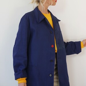 Pu&ograve; includere: Giacca blu navy con colletto e tre bottoni. &Egrave; visibile un bottone rosso. C'&egrave; una tasca sul petto. Le maniche arrotolate rivelano una maglietta gialla a maniche lunghe. La giacca &egrave; indossata sopra una maglietta gialla.