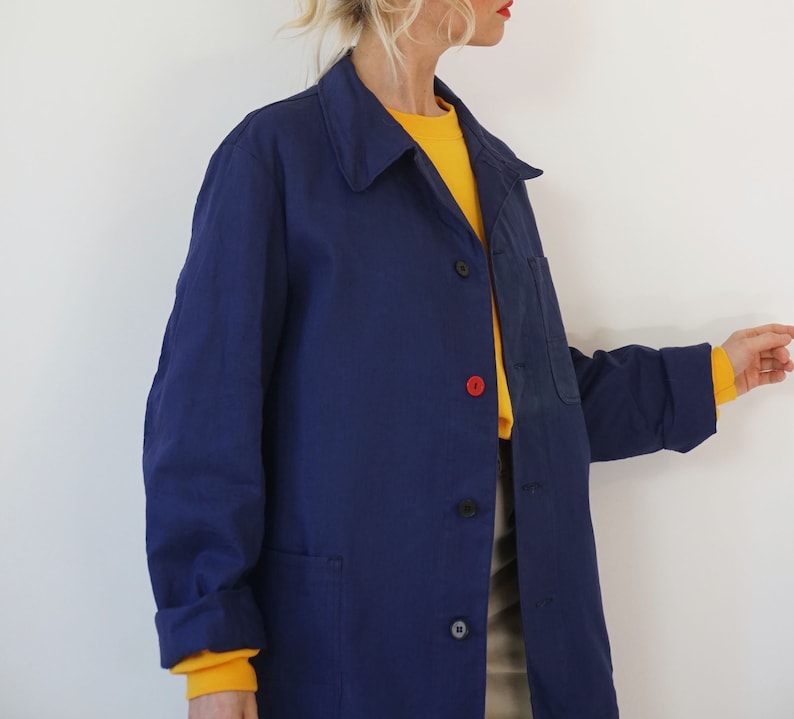 Pu&ograve; includere: Giacca blu navy con colletto e tre bottoni. &Egrave; visibile un bottone rosso. C'&egrave; una tasca sul petto. Le maniche arrotolate rivelano una maglietta gialla a maniche lunghe. La giacca &egrave; indossata sopra una maglietta gialla.