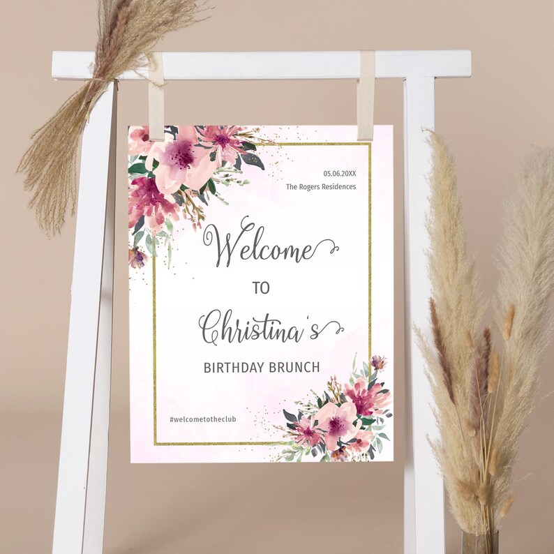 May include: A welcome sign for a birthday brunch with a pink floral design and gold glitter accents. The sign reads "Welcome to Christina's Birthday Brunch #welcometotheclub".