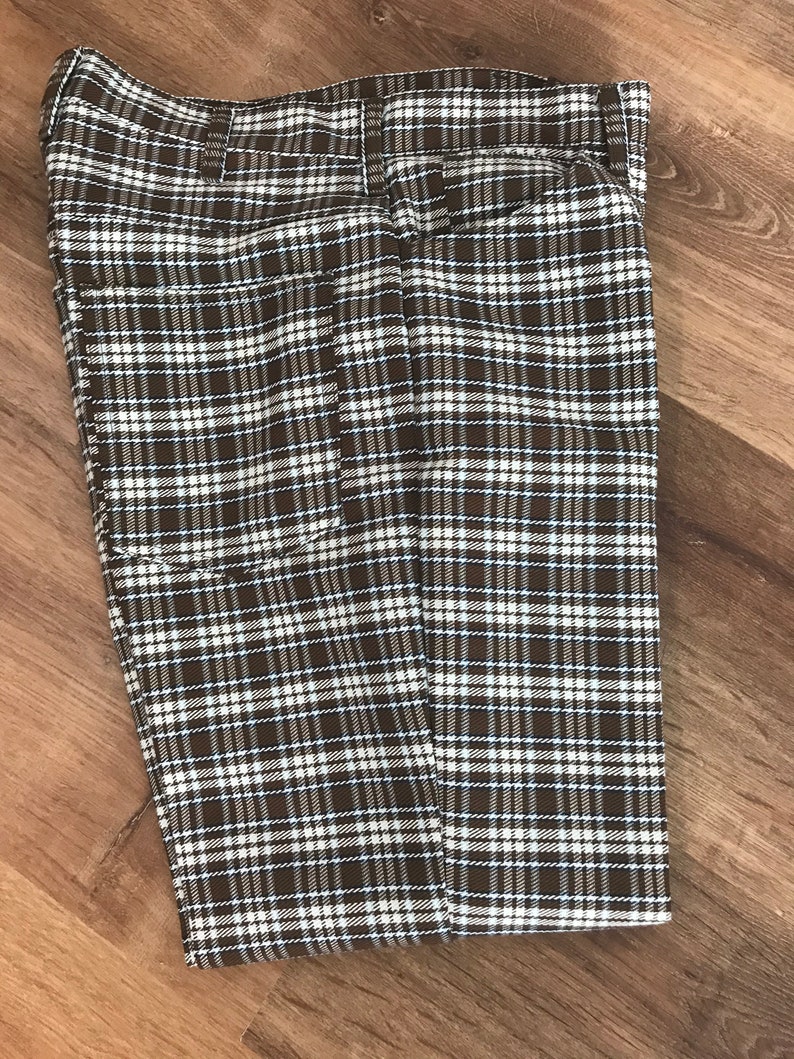 May include: A pair of brown and white plaid pants folded in half. The pants have a blue and white plaid pattern.