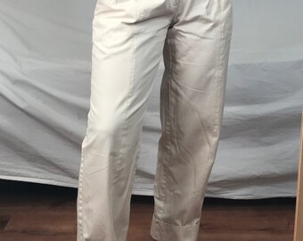 May include: High-waisted, cream-colored pants with pleats and cuffed hems. The pants have a button closure and a zipper fly.