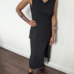May include: A black and white striped sleeveless dress with a side slit. The dress is made of a lightweight fabric and has a v-neckline.
