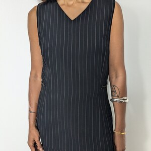 May include: A black and white striped sleeveless dress with a v-neckline and a side slit.