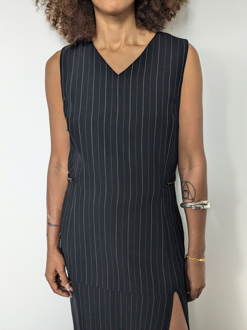 May include: A black and white striped sleeveless dress with a v-neckline and a side slit.