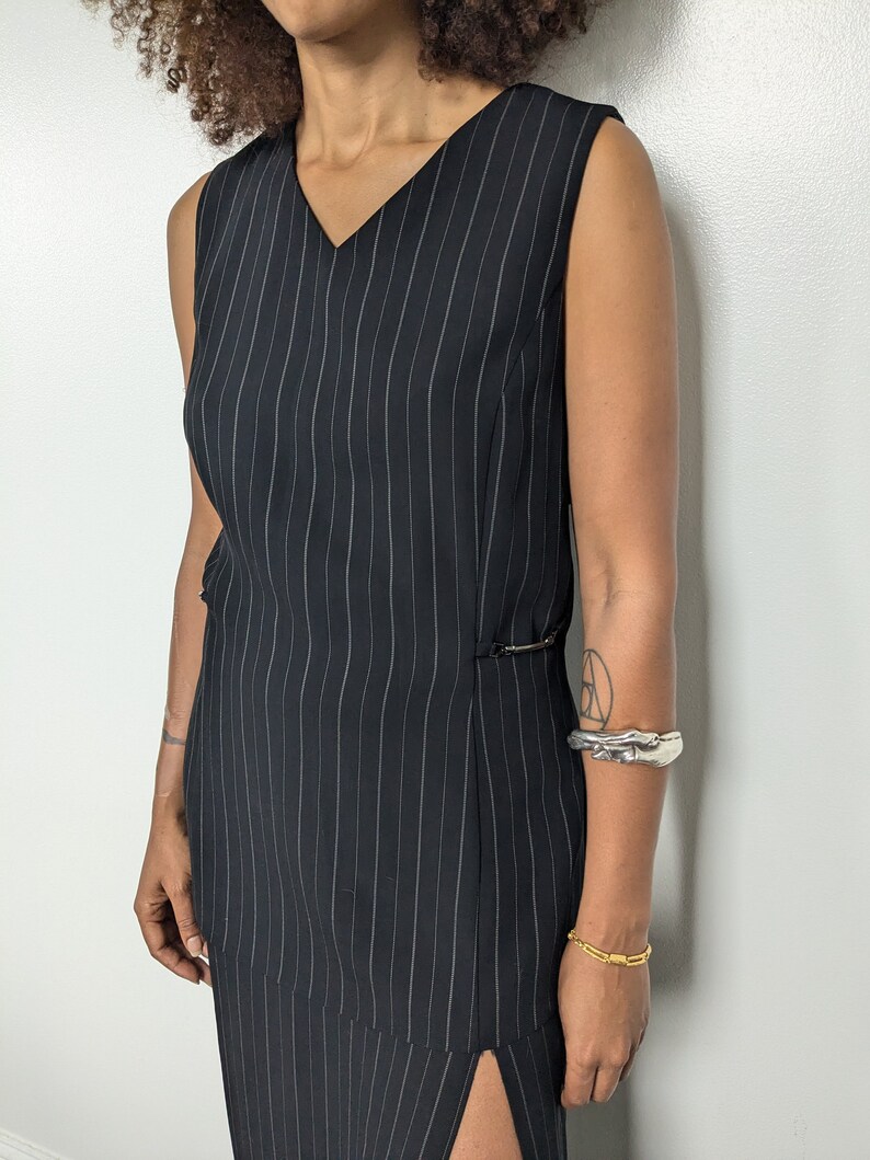 May include: A black and white striped sleeveless dress with a v-neckline and a side slit. The dress is made of a lightweight fabric and has a relaxed fit.