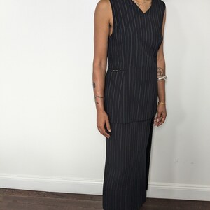 May include: A black and white striped sleeveless dress with a V-neckline. The dress has a fitted bodice and a flowing skirt.