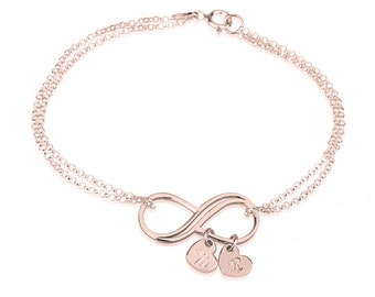 May include: A rose gold infinity bracelet with two small heart charms. The charms are engraved with the initials "M" and "R".