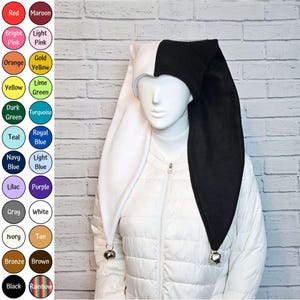May include: A two-toned jester hat featuring a white left side and a black right side, each long point finished with a small silver bell. The hat is displayed on a mannequin wearing a white quilted jacket, with a colour chart showing various options.