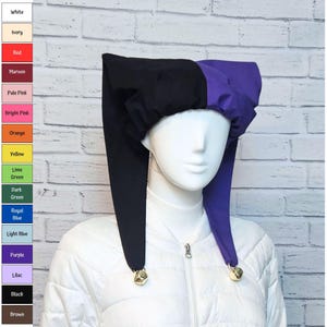 May include: A two-toned jester hat featuring a black section and a purple section. The hat has two long, pointed fabric tails that hang down on either side, each finished with a small metallic bell at the tip. The hat is displayed on a mannequin.