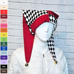 May include: A jester hat featuring a black and white diamond pattern alternating with solid red fabric panels. The hat has two long, pointed tails that hang down on either side, each finished with a small metallic bell at the tip, worn on a mannequin.