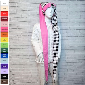 May include: A long jester hat featuring a black and white diamond pattern on one side and solid pink fabric on the other. The hat has two long, dangling tails, each finished with a small silver bell at the tip, worn on a white mannequin.