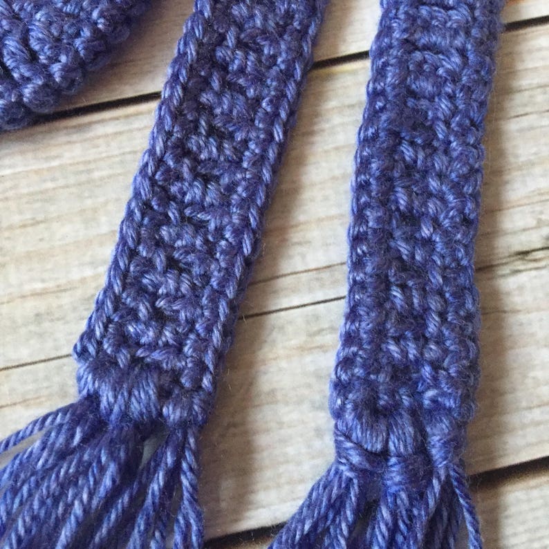 May include: Two blue crocheted tassels with fringe. The tassels are made with a textured stitch and have a long, flowing fringe.