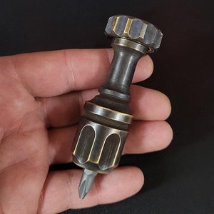 May include: A small, brass screwdriver with a knurled handle and a Phillips head bit.