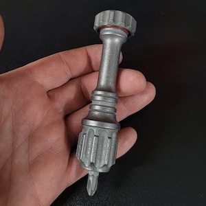 Puede incluir: Un destornillador de metal plateado con un mango texturizado y una punta pequeña y puntiaguda.