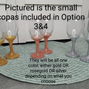 May include: Four small wine glasses with gold, rose gold, and silver glitter. The text "Pictured is the small copas included in Option 3&4" is visible in the image.