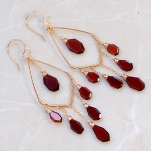 Peut inclure: Une paire de boucles d'oreilles pendantes en or avec un cadre en forme de larme et plusieurs perles de pierres précieuses rouges pendantes.