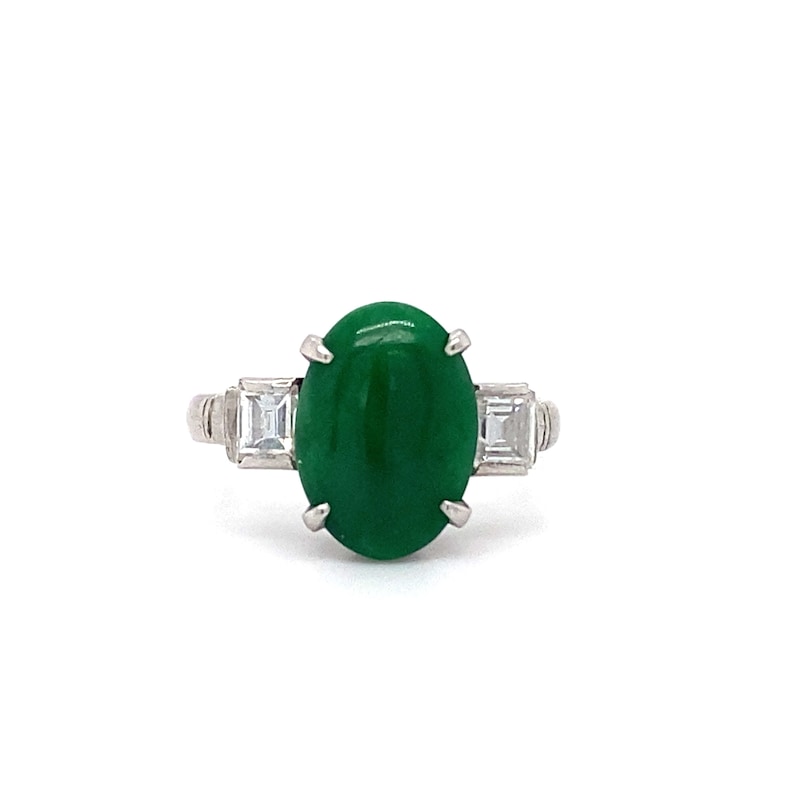 May include: A platinum ring with a large oval cabochon green jade stone and two smaller baguette-cut diamonds on either side.