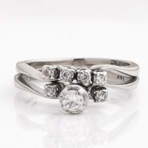 May include: A white gold diamond engagement ring set with a center stone and a band of smaller diamonds.