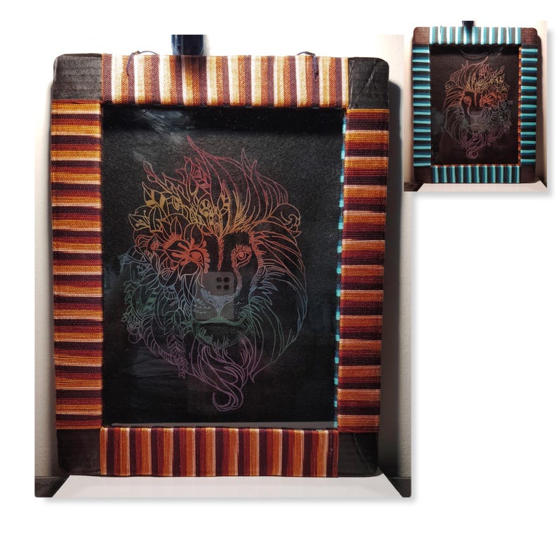 May include: A framed picture with a black background and a rainbow colored line drawing of a lion's face. The frame is made of wood and has a brown, orange, and white striped border.