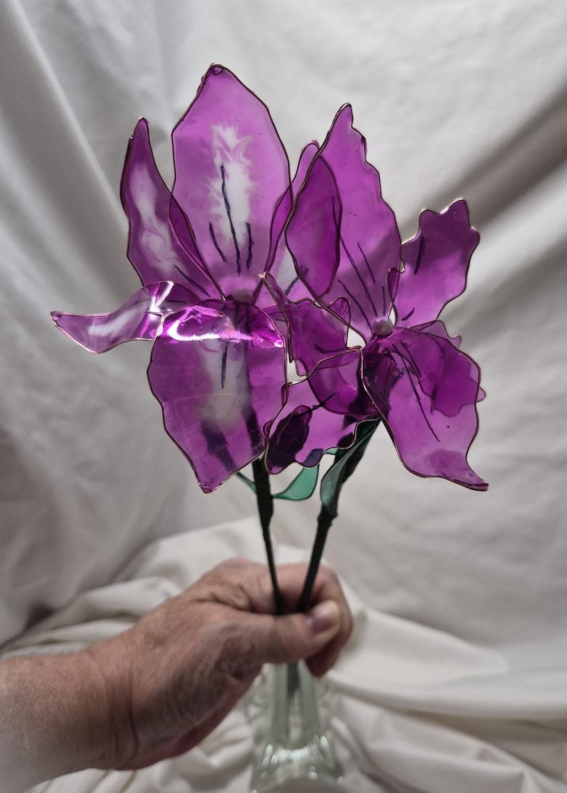 May include: Two artificial flowers with translucent, deep purple petals crafted from a thin, flexible material. Each flower features dark, wire-like stems and delicate, vein-like markings on the petals, creating a realistic, layered floral appearance.