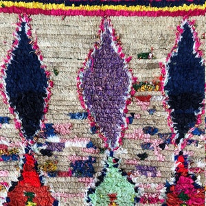 May include: A colorful Moroccan rug with a geometric pattern. The rug is made of wool and has a fringe border. The colors in the rug include red, blue, green, yellow, and white.