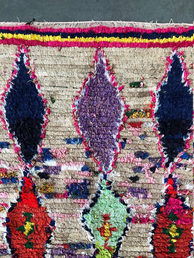 May include: A colorful Moroccan rug with a geometric pattern. The rug is made of wool and has a fringe border. The colors in the rug include red, blue, green, yellow, and white.