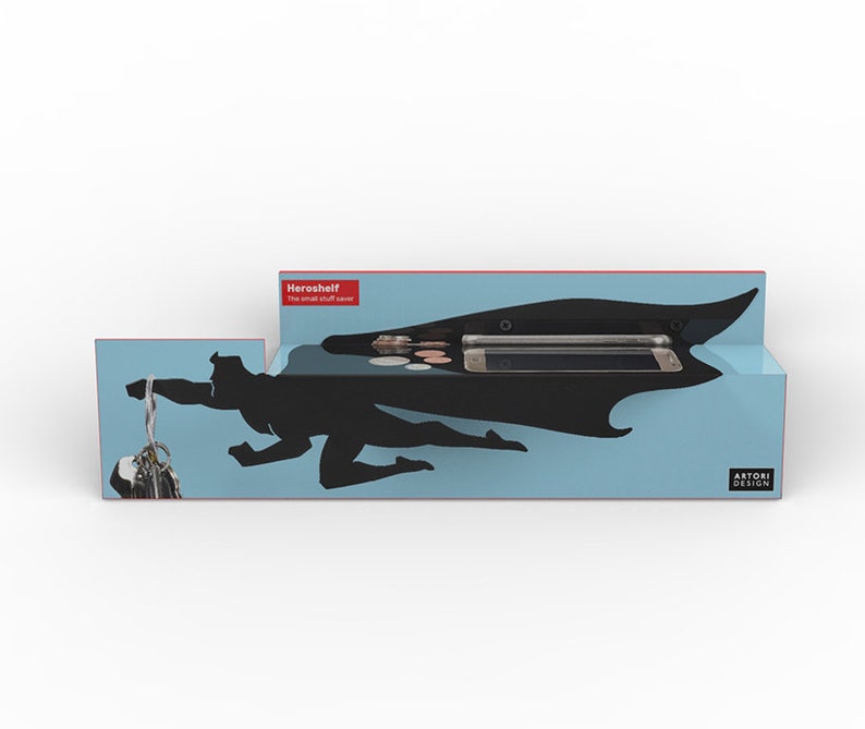 Op de afbeelding: Een blauw en zwart Heroshelf met een superheld silhouet ontwerp. De plank heeft compartimenten voor een telefoon, munten en sleutels. De tekst "Heroshelf The small stuff saver" is zichtbaar.